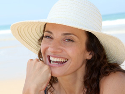 Picture of a happy woman wearing a sun hat and enjoying the beach 