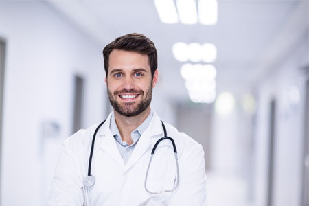 Picture of a plastic surgeon wearing a white hospital gown smiling back at the camera