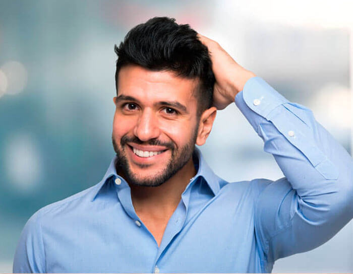 Picture of a man with his hand on his hair showing he is happy with his Costa Rica hair transplant procedure.