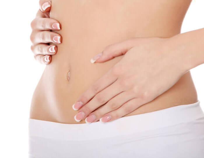 Picture of a woman showing her slim abdomen after a tummy tuck with liposuction of the abdomen and waist procedure in Costa Rica.